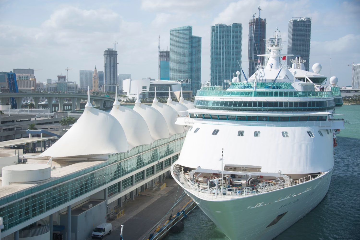 A cruise ship berthed at the Port of Miami terminal with the downtown skyline behind A cruise ship berthed at the Port of Miami terminal with the downtown skyline behind