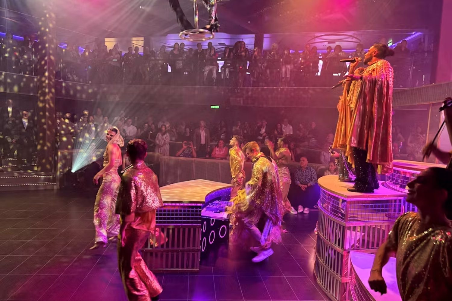 Two performers seated beneath a hanging canopy of roses in Chapters, with a flowered landscape on the LED wall behind Two performers seated beneath a hanging canopy of roses in Chapters, with a flowered landscape on the LED wall behind